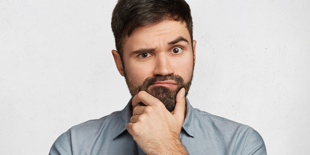A bearded man holding his chin